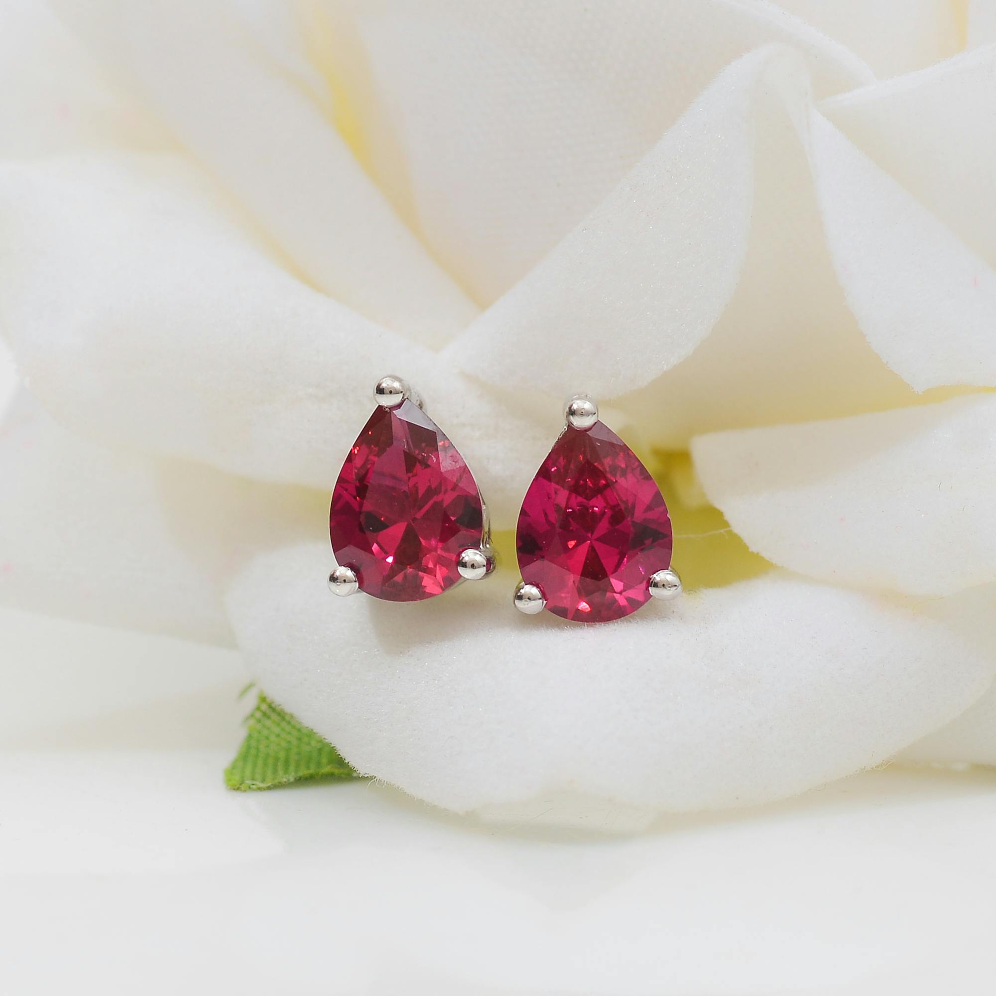 Pair of red teardrop-shaped earrings on a white floral background